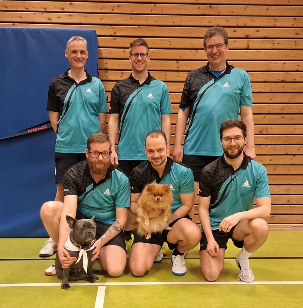 Die erste Tischtennis-Mannschaft des TSV Hirsau posiert in der Sporthalle, zwei Hunde sitzen mit auf dem Mannschaftsfoto.