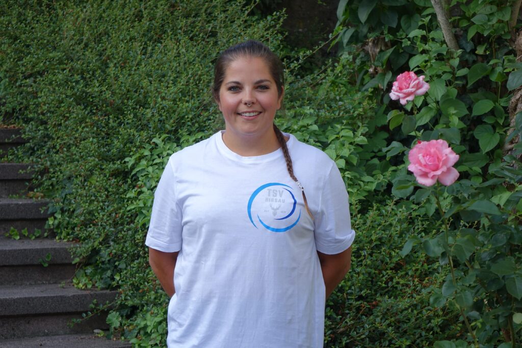 Jessi vom TSV Hirsau steht vor einer blühenden Hecke und lächelt freundlich in die Kamera.