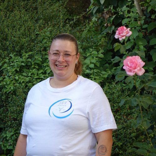 Julia Binder-Rieger – Geschäftsstelle TSV Hirsau Julia Binder-Rieger, Ansprechpartnerin der Geschäftsstelle des TSV Hirsau, vor blühender Hecke fotografiert